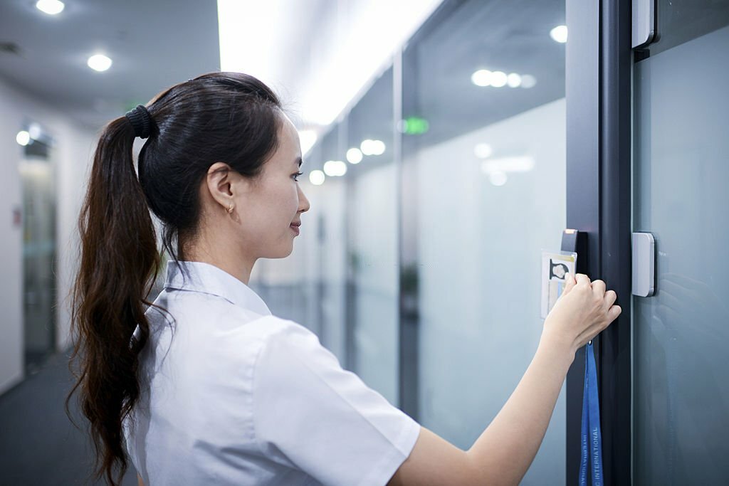 A business woman is using card open the electronic door of office
